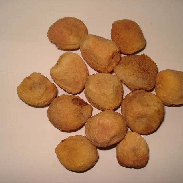 Sun-dried apricots arranged on a light surface.