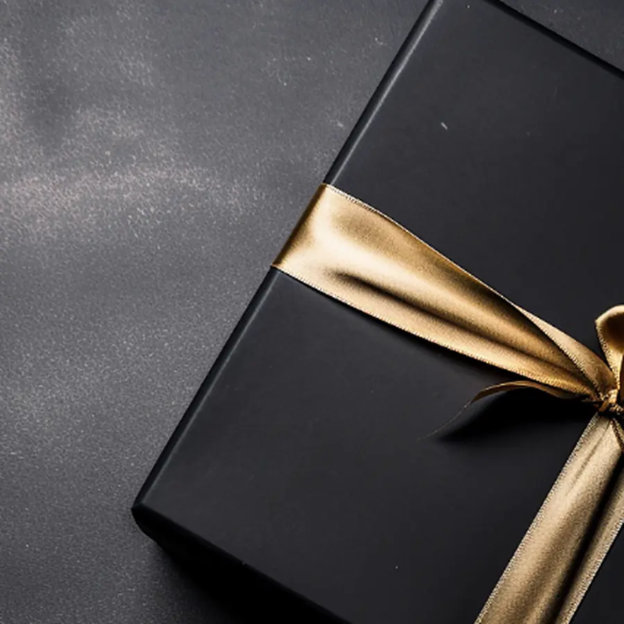 A black gift box with a gold satin ribbon.